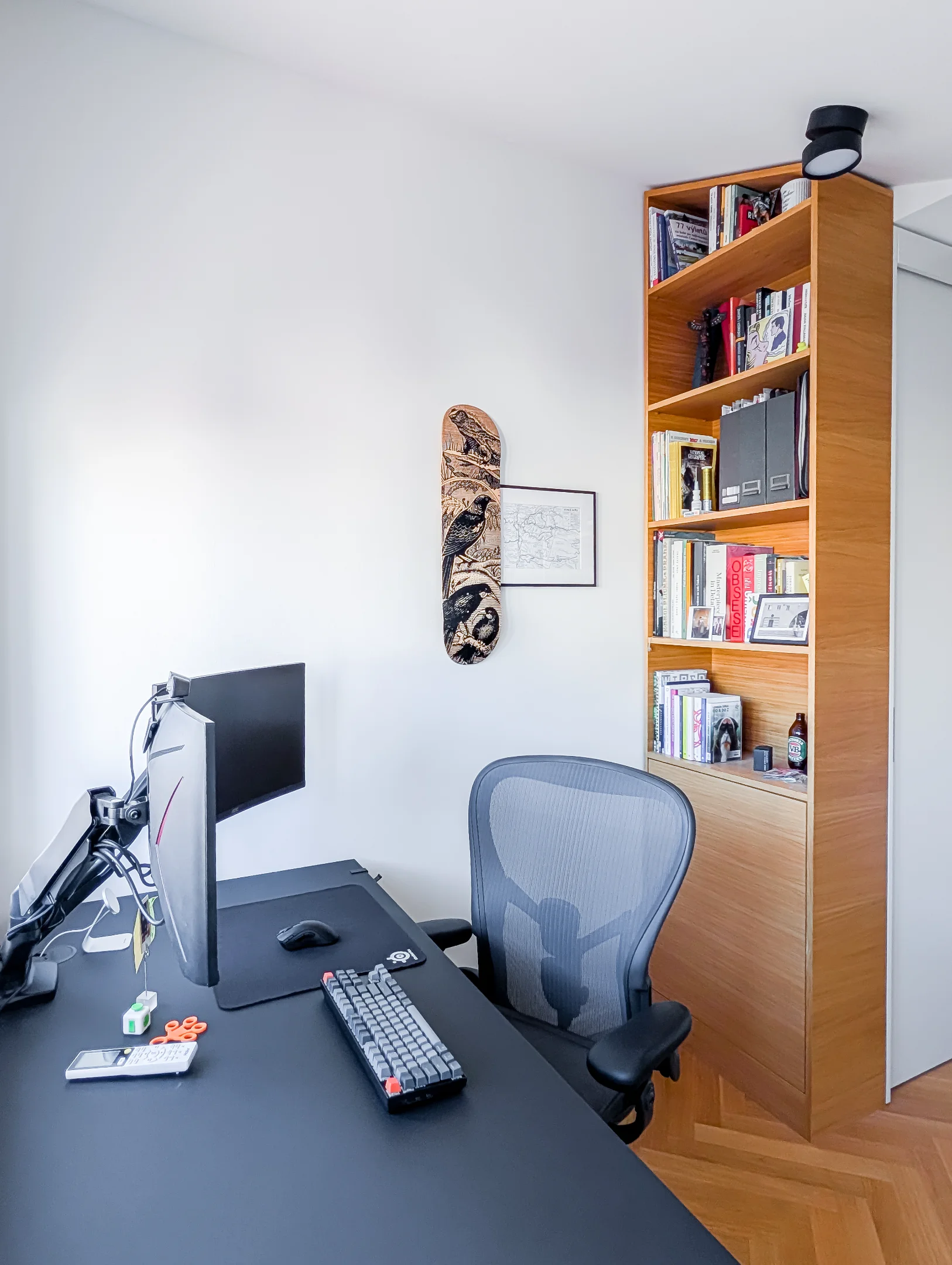 Pracovna s psacím stolem, židlí a dřevěnou knihovnou.